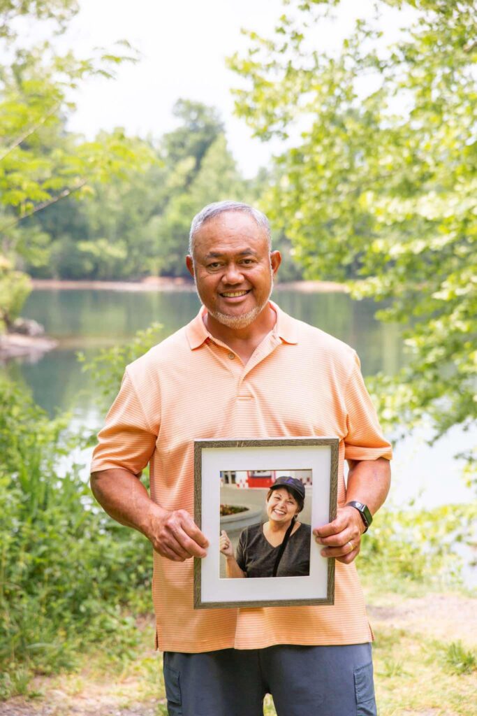 Man holding a framed image of his wife who recently passed away