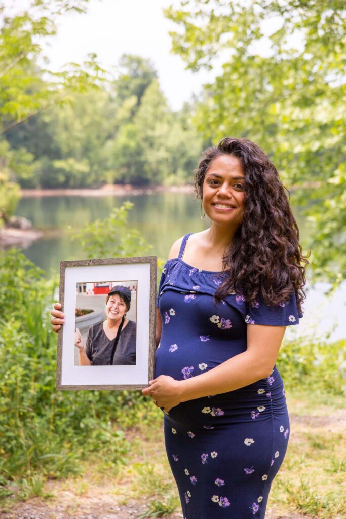 Pregnant woman holding a framed image of her mother who passed away a week prior to this image.  